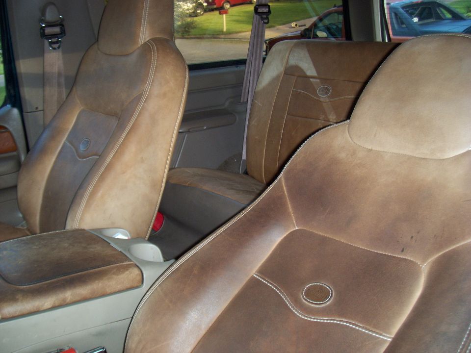 Brown leather bucket seats with white stitching inside a vehicle.