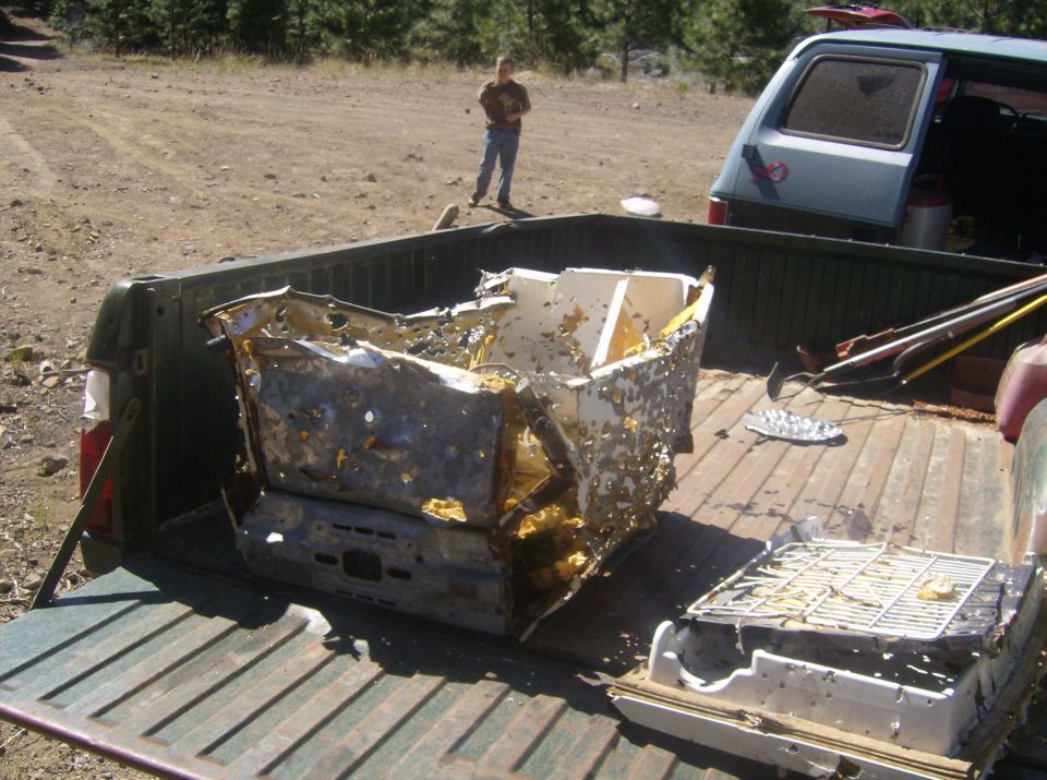 Pickup truck bed with damaged metal debris and a person in the background.