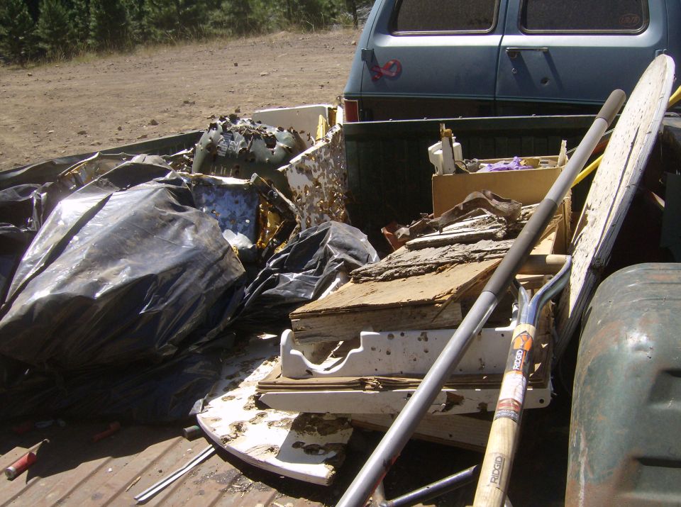 Debris filling the bed of a pickup truck, with a blue van in the background.