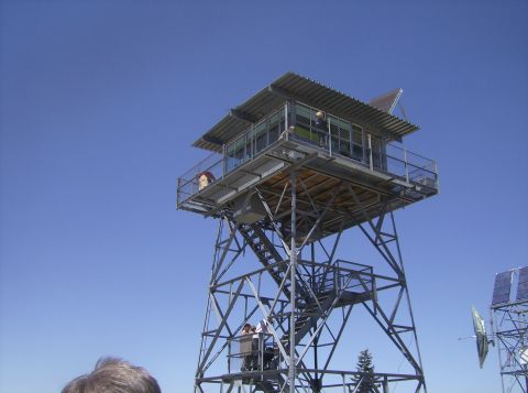 1986 Ford Bronco - A tall fire lookout tower stands against a clear blue sky. The tower has multiple levels with stairs and railings, and a small enclosed cab…