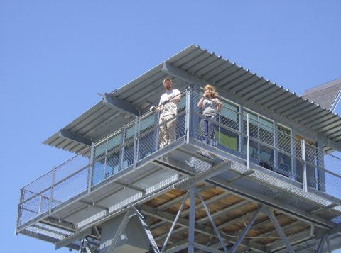 1986 Ford Bronco - Two people stand on the observation deck of a metal tower against a clear blue sky.