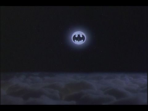 1988 Mercury Grand Marquis - A dark night sky with stars is visible above a layer of clouds. A glowing Batman symbol is projected in the sky.