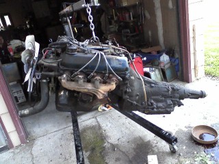 1979 Ford Bronco - Engine and transmission assembly on a stand, likely being worked on in a garage.