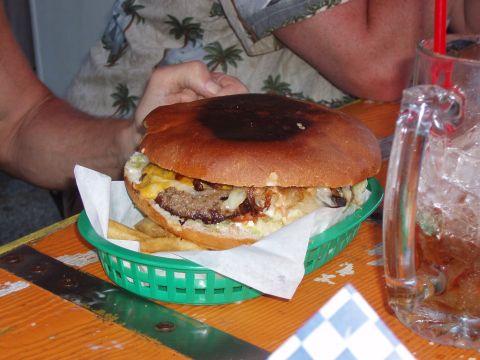 1992 Ford Taurus - A large burger and fries served in a green basket on a table, next to a glass of iced tea.
