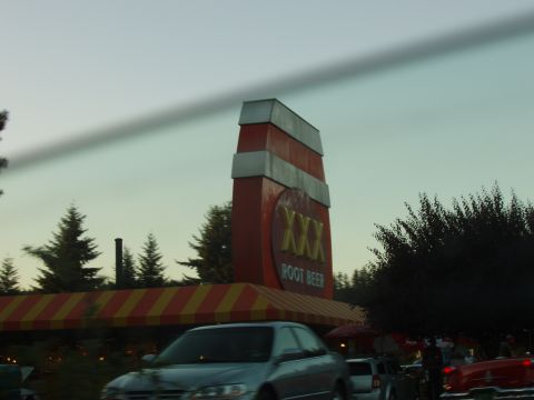 1992 Ford Taurus - A silver sedan is seen driving past a XXX Root Beer establishment.