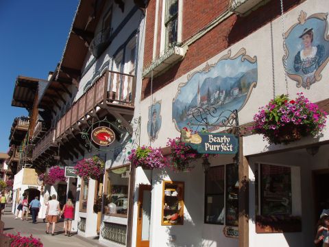 1992 Ford Taurus - A charming street scene unfolds with traditional architecture adorned with flower baskets and murals, as pedestrians stroll along the sidew…