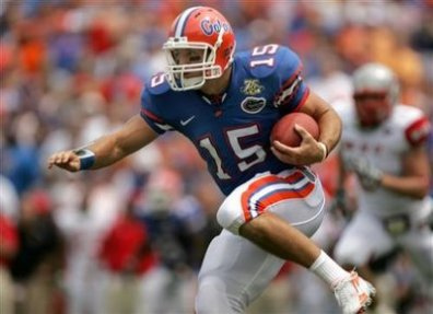 1992 Ford Bronco - A college football player in a blue Florida Gators number 15 jersey and white helmet runs with the ball tucked under his right arm, with op…