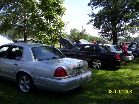 2008 Ford Crown Victoria - Several Ford Crown Victorias are displayed outdoors on a sunny day, with some hoods open.