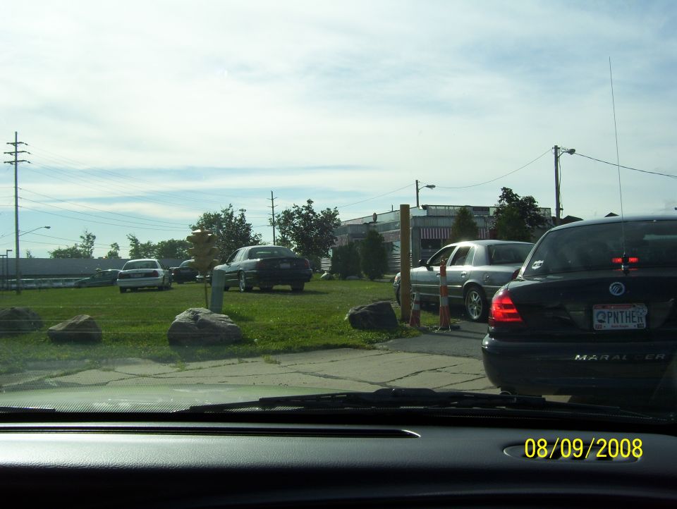 Several cars parked on grass and pavement, with a date stamp of 08/09/2008