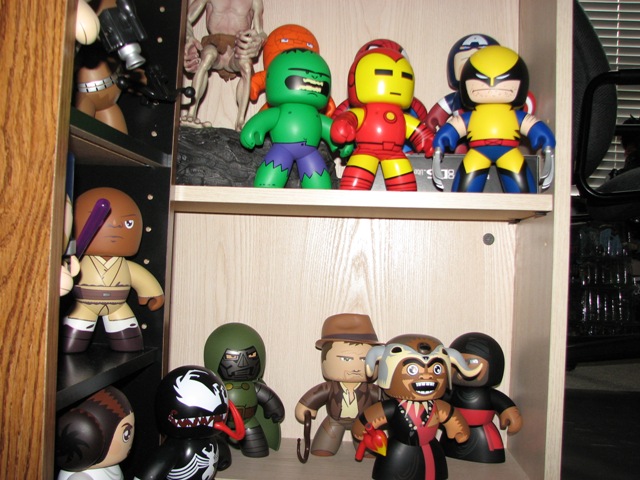 shelf with various action figures including Hulk, Iron Man, Wolverine, Obi-Wan Kenobi, Indiana Jones, and Doctor Doom