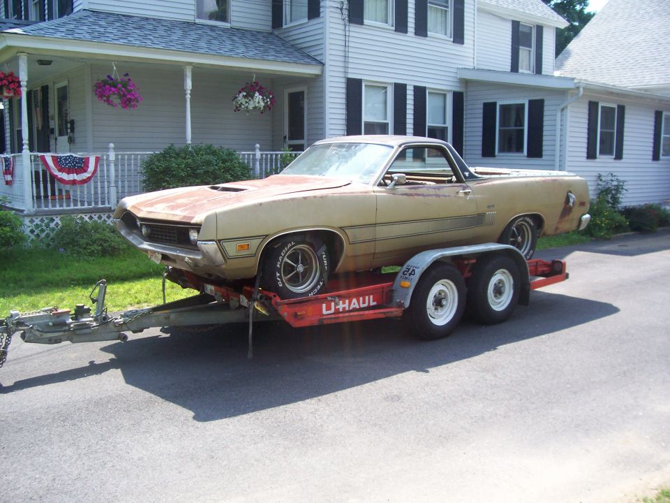 Tan vintage Ranchero-style car-pickup loaded on a U-Haul trailer