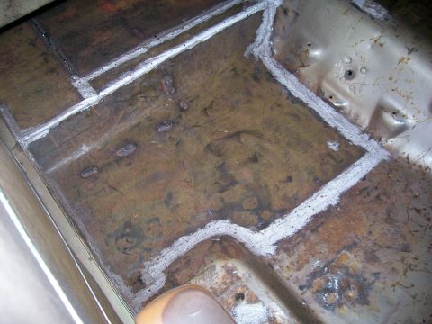 1970 Ford Ranchero - Close-up of a vehicle's floor pan showing rust and sealant application.