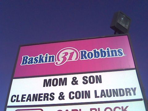 1992 Ford Bronco - A sign displays Baskin Robbins and Mom & Son Cleaners & Coin Laundry under a blue sky.