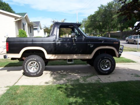 1986 Ford Bronco - Side view of a lifted Ford Bronco with two-tone paint and aftermarket wheels.