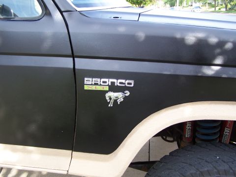 1986 Ford Bronco - Close-up of the Bronco XLT emblem on the fender of a two-tone SUV.