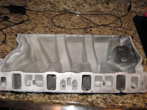1991 Ford Bronco - An aluminum intake manifold is shown on a granite countertop, with electrical cords in the background.