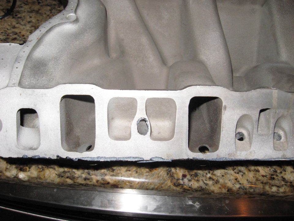 Aluminum intake manifold with four intake ports visible, resting on a granite countertop