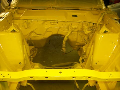 1970 Ford Ranchero - The engine bay of a vehicle has been painted bright yellow, with the engine removed and suspension components visible.
