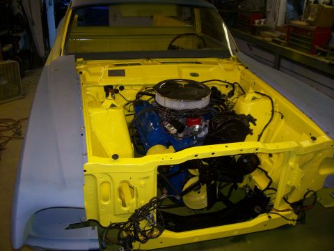 1970 Ford Ranchero - The engine bay of a yellow 1970 Ford Ranchero shows a blue engine and an unfinished gray fender.