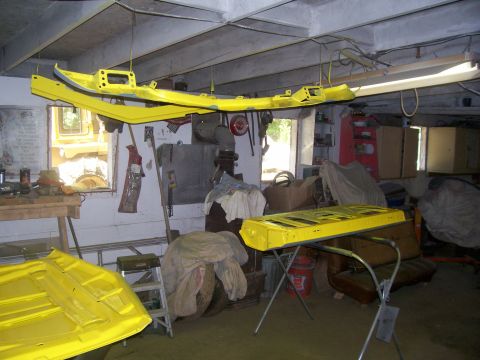 1970 Ford Ranchero - Car parts are suspended and resting on a stand, undergoing a painting process in a cluttered garage.