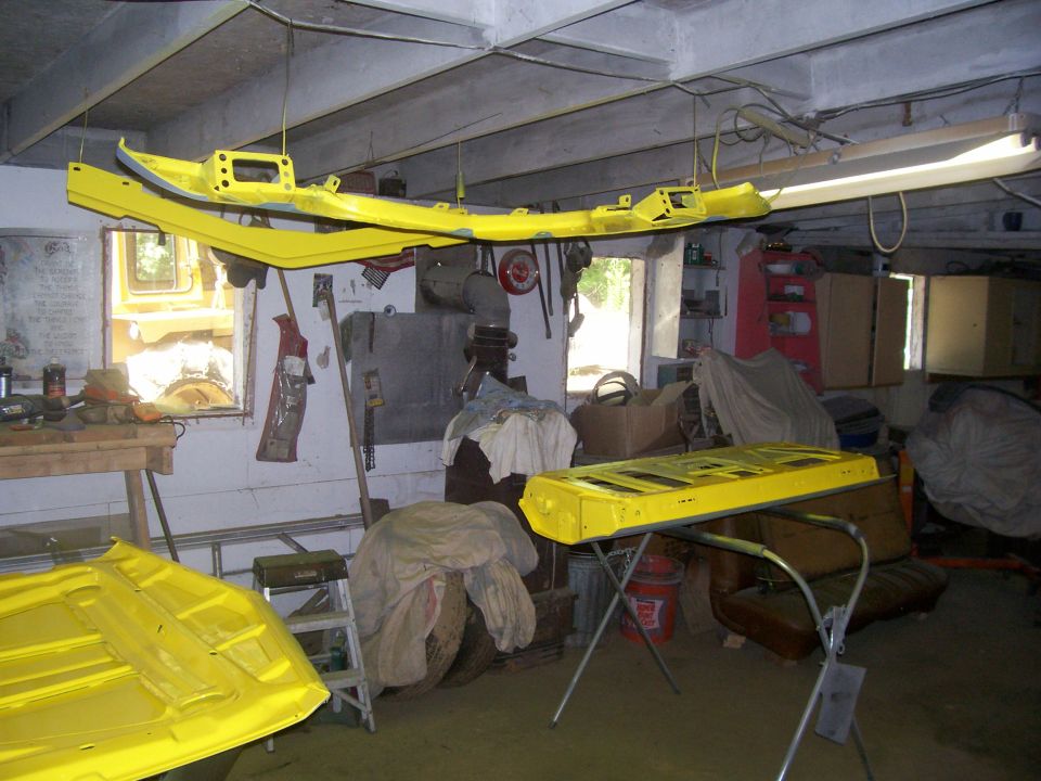 Freshly painted yellow body panels and core support drying in a home garage shop