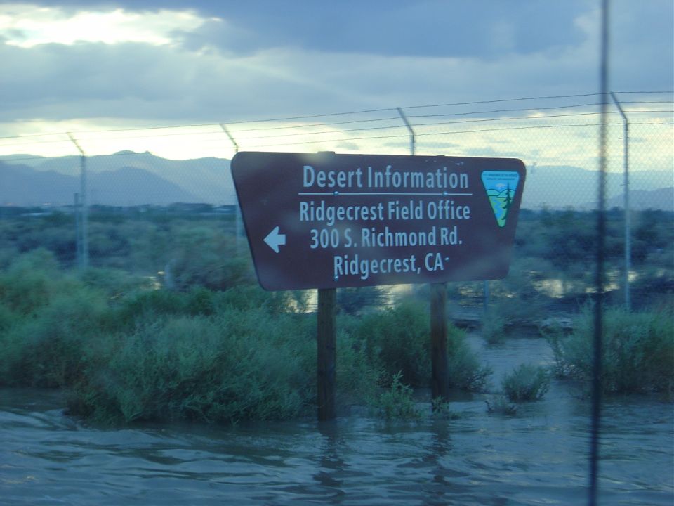 Sign for Desert Information Ridgecrest Field Office in flooded desert.