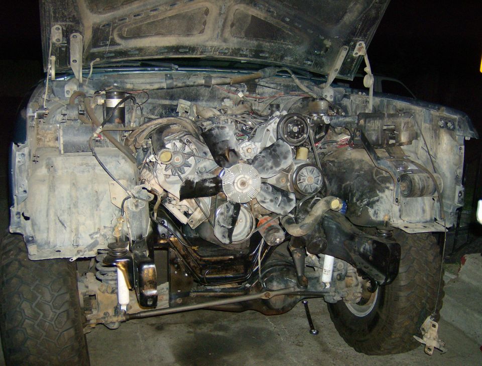 Front engine and frame of a dirty diesel truck with hood up and fan exposed
