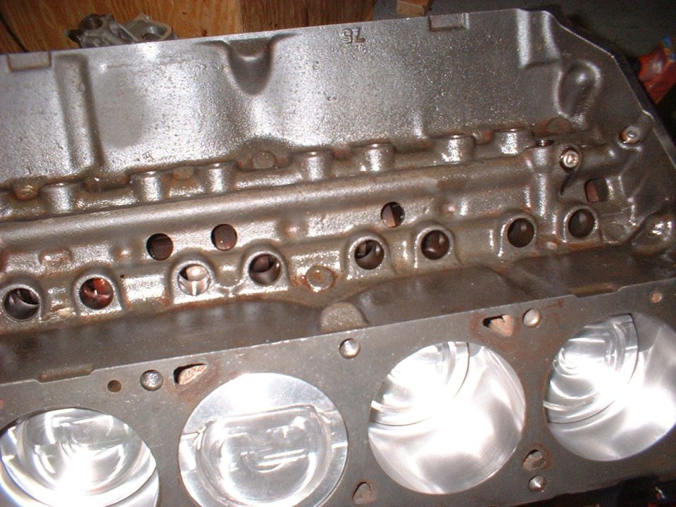 V8 engine block deck with pistons in the bores and a '75' casting mark