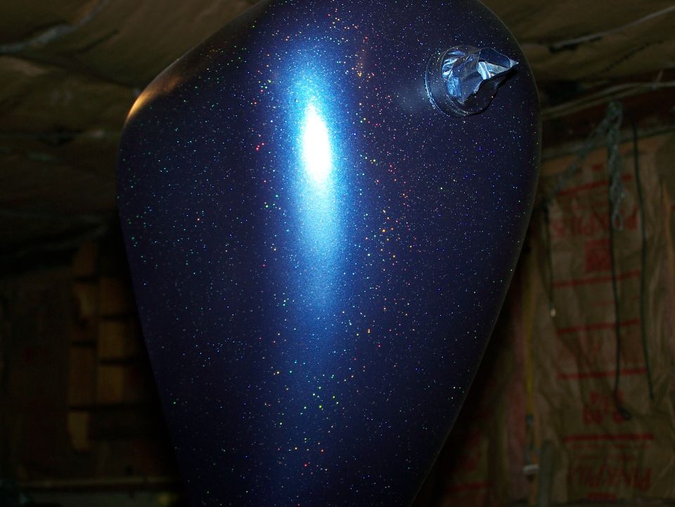 Blue metalflake motorcycle fuel tank hanging in a workshop
