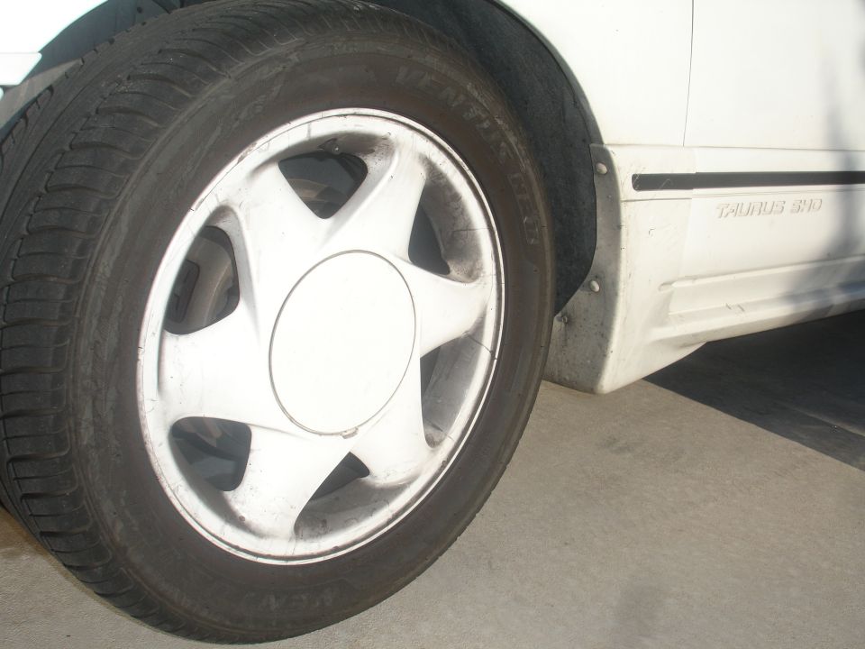 White Ford Taurus front passenger wheel and fender with Taurus SHO badging.