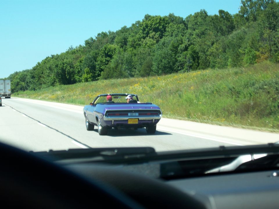 Purple convertible muscle car driving on a highway.