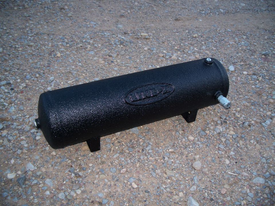 Black textured air tank with fittings and legs on gravel