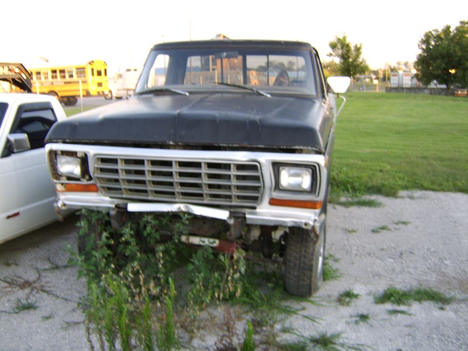 Front view of a black Ford pickup with weeds at the bumper