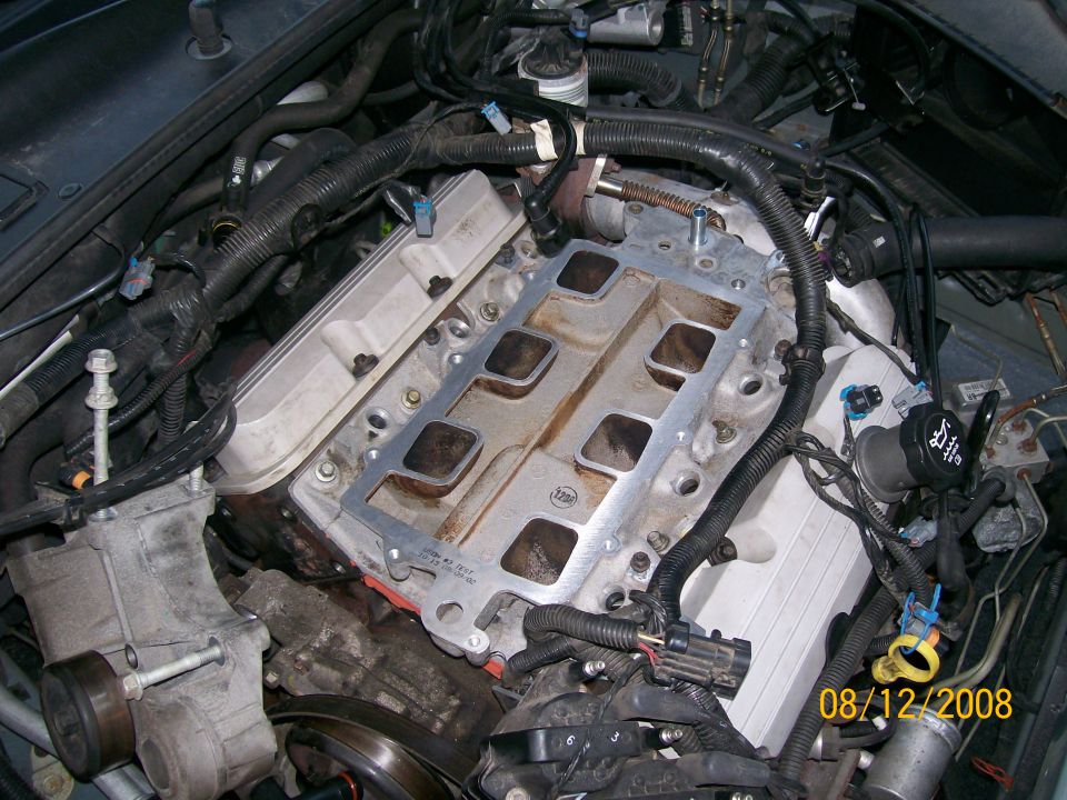 Close-up of a V8 engine with intake manifold removed, showing gasket and cylinder heads.