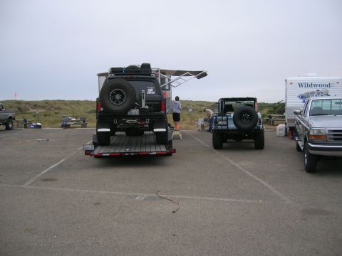 1996 Ford Bronco - A black Ford Bronco is loaded onto a trailer, parked on asphalt near a beach with a light blue Jeep and a silver Ford pickup truck. The Bro…
