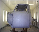 2007 Ford Mustang - Photograph of a primered truck cab in a paint booth, not a technical document.