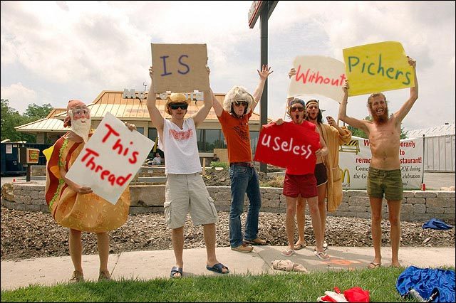 People holding signs in front of a McDonald's, one in a hot dog costume.