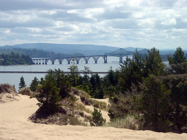 Coastal sand dune overlook with steel arch highway bridge crossing a bay