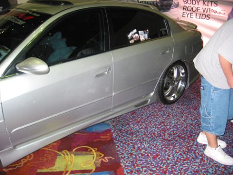2002 Nissan Altima - A silver sedan is shown from the side, custom wheels and tinted windows.