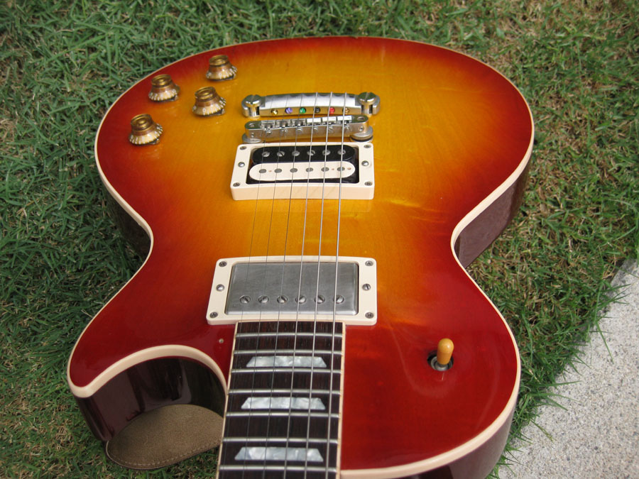 Sunburst electric guitar with chrome hardware and white pickup covers on grass