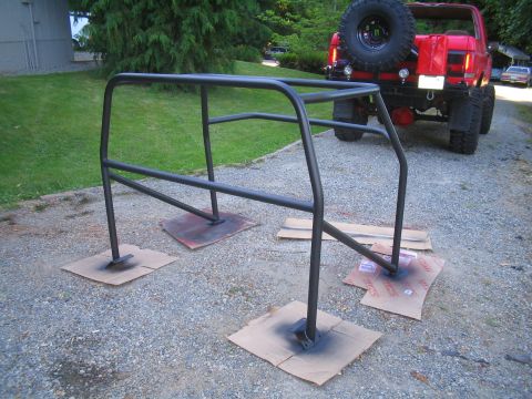 1989 Ford Bronco - A custom roll cage is being painted in front of a red 1989 Ford Bronco.