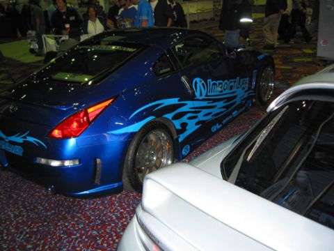 2002 Nissan Altima - A blue sports car with flame decals is parked next to a white car, with "SUPERMOTORS" visible on the white car's windshield.