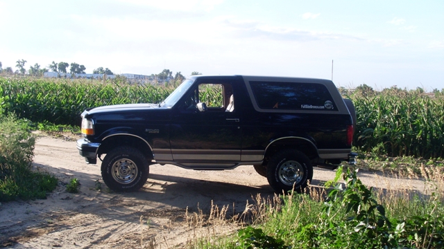1996 Ford Bronco parked on a dirt road next to a cornfield