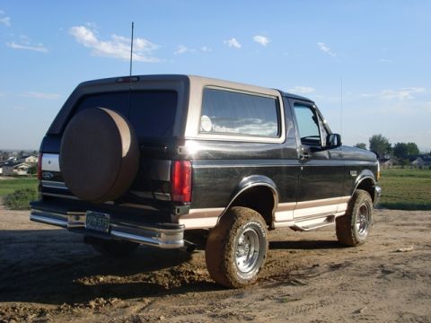 1996 Ford Bronco - This 1996 Ford Bronco is shown from the rear, parked on a dirt lot with houses in the background.