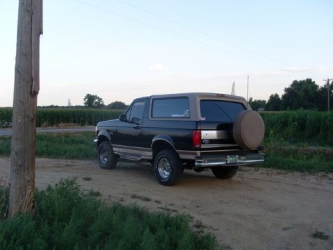 1996 Ford Bronco - A 1996 Ford Bronco is parked on a dirt road with a field in the background.