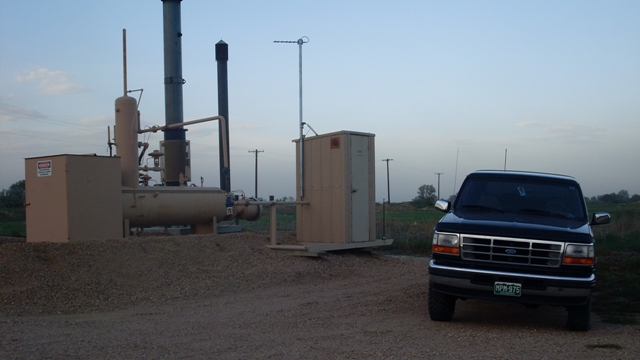 Black 1996 Ford Bronco parked on gravel in front of industrial equipment under a pale sky