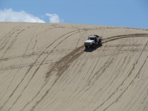 1996 Ford Bronco - 1996 Ford Bronco navigates a sandy incline, leaving tire tracks on the dune.