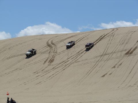 1996 Ford Bronco - SUVs navigating sand dunes under a partly cloudy sky.