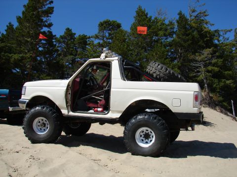 1996 Ford Bronco - Modified 1996 Ford Bronco with a roll cage and large tires parked on sand dunes.