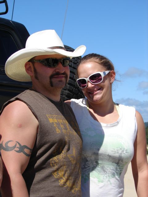 1996 Ford Bronco - A man and woman pose for a photo with a spare tire visible behind them.